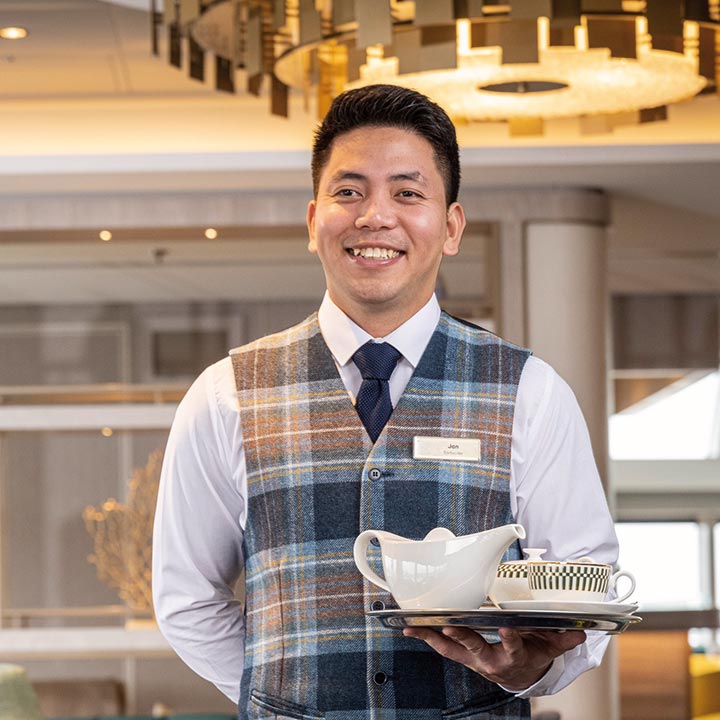 A waiter serving tea in the Britannia Lounge on Spirit of Adventure A waiter serving tea in the Britannia Lounge on Spirit of Adventure